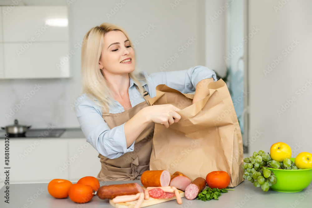 Indoors. Young woman unpacking lunch box in the kitchen