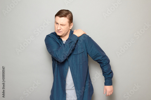 Studio shot of unhappy mature man suffering from pain in shoulder © Andrei Korzhyts