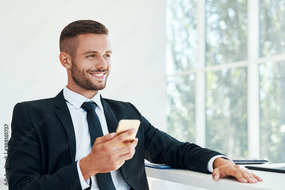 Portrait of smiling businessman with mobile phone in modern officedfer Portrait of smiling businessman with mobile phone in modern officedfer