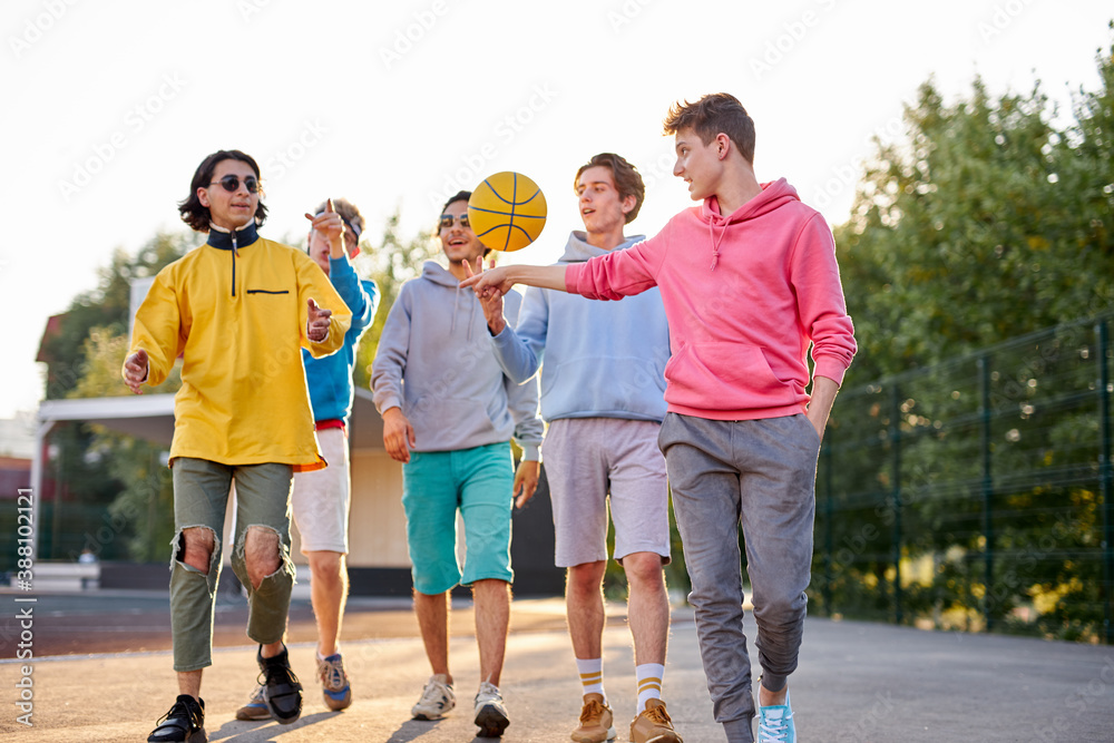 Obraz premium portrait of positive group of young people came to play basketball, in casual wear. caucasian boys enjoy time together outdoors