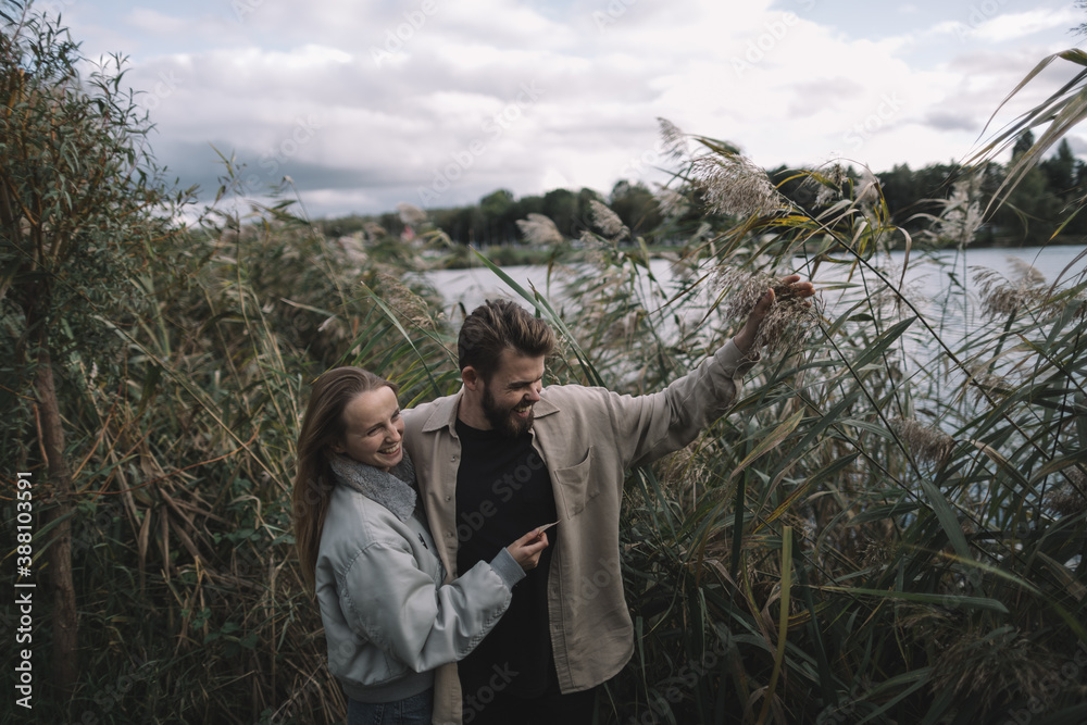 a loving couple stands in the reeds against the backdrop of a lake in the evening and communicates