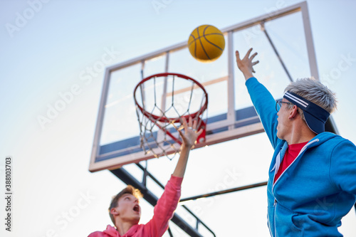 young caucasian basketball players in action flying high and scoring, at playground