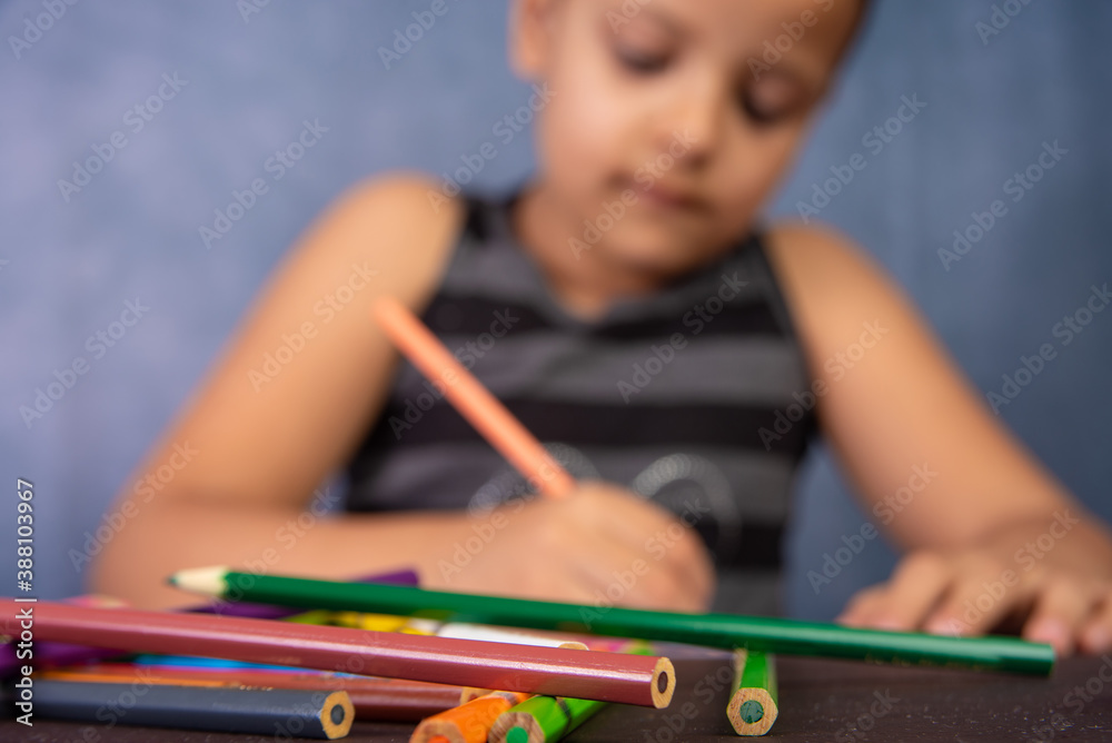 Little Brazilian girl drawing with colored pencils, selective focus on the foreground, colored pencils.