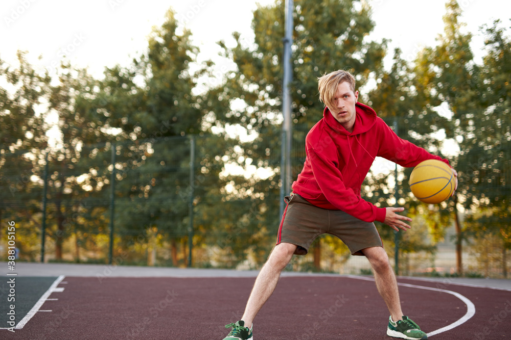 confident basketball gamer play outdoors, looks away, on competition