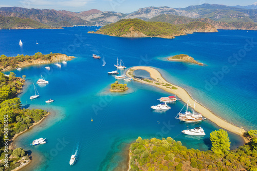 Fototapeta Naklejka Na Ścianę i Meble -  aerial view to long sand cape with beautiful lagoon with sailing boats and mountains on horizon in Turkey 
