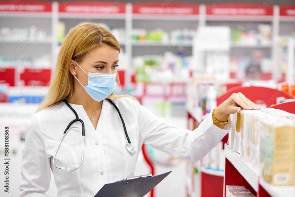 female pharmacist fulfilling a prescription holding drugs in hand, she is checking the script