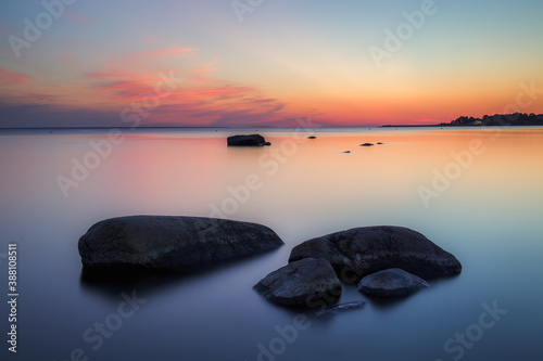 Stones on sea coast. Sunset over the sea. Deep blue color of summer late sunset. Long exposure