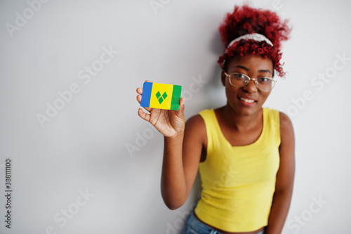 African american woman with afro hair, wear yellow singlet and eyeglasses, hold Saint Vincent and the Grenadines flag isolated on white background. photo