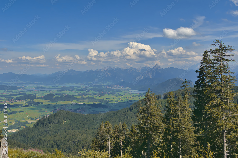 Landschaftsblick mit Blick auf Bäume, Tal, Gebirge und blauen Himmel mit weißen Wolken.