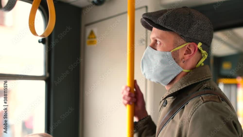 A man wearing a mask rides on public transport, looks out the window. Transportation of passengers in the city. Respiratory protection rule in a public place. A man wearing a mask rides on public transport, looks out the window. Transportation of passengers in the city. Respiratory protection rule in a public place.