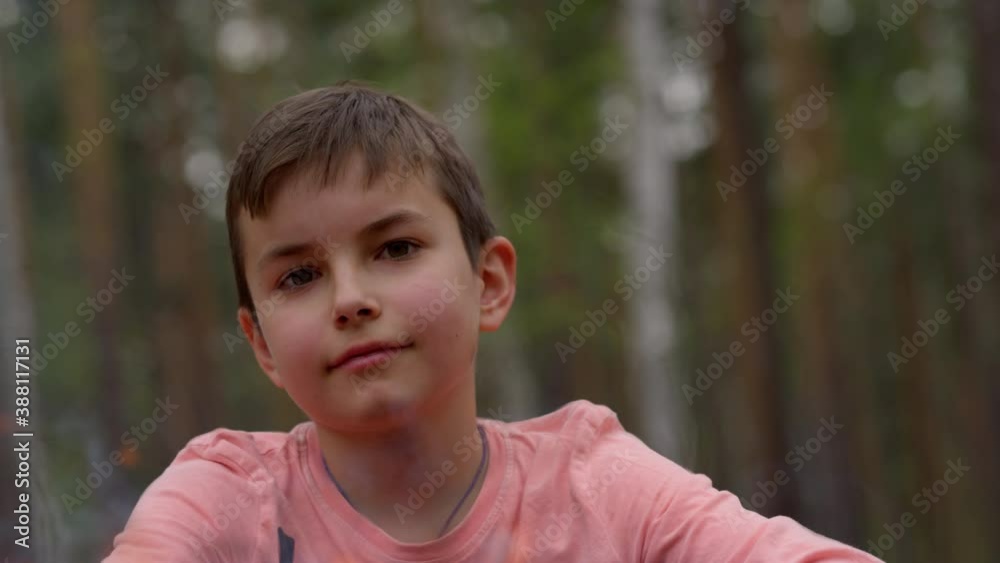 Close up on cute teenager smiling to camera near bonfire in forest. Close up on cute teenager smiling to camera near bonfire in forest.