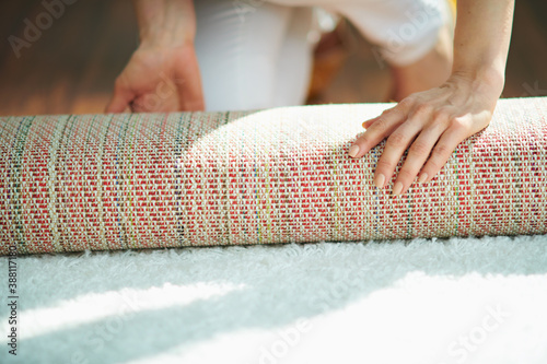 Obraz na plátně woman in house in sunny day folding carpet into roll