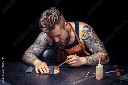 Craftsman working with leather cuts out leather goods in the tanner shop photo