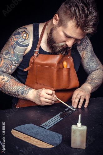 Leather Craftsman works with leather in his workshop photo