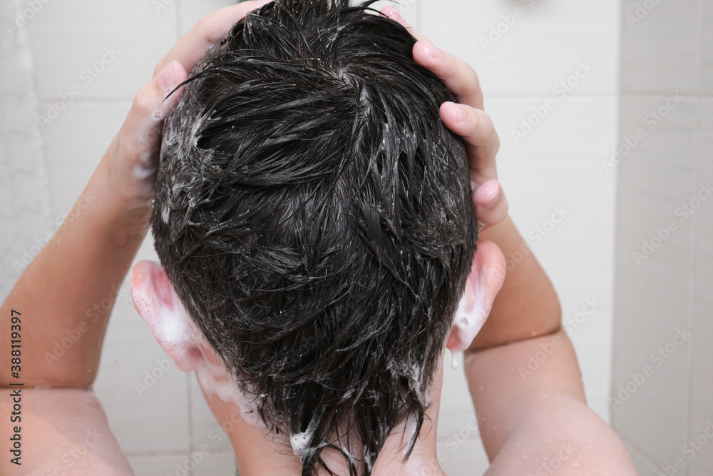 Naklejka premium Hygienic procedures and healthy habits of a preteen boy - taking shower and washing hair with shampoo