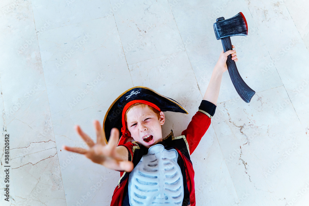 Horizontal view of little caucasian kid playing with Halloween pirate  costume at home holding a toy ax. Seasonal and festive Halloween party  concept. Stock Photo | Adobe Stock