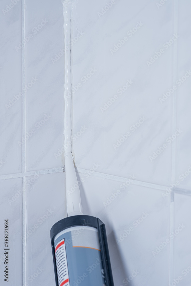 Plumber Applying silicone sealant to the tile joint