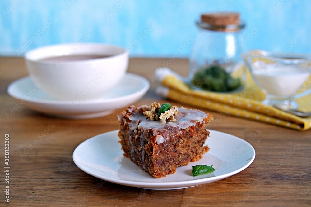 Dessert, a portion of carrot cake with walnuts and almonds on a white plate. Decorated with walnuts and icing. Dessert, a portion of carrot cake with walnuts and almonds on a white plate. Decorated with walnuts and icing.