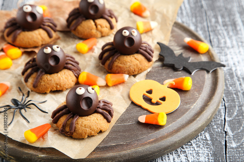 Halloween cookies with chocolate spiders and candies on wooden table
