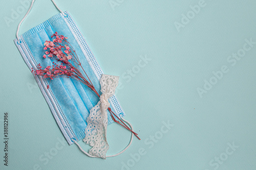 dry flower with lace and a medical mask on a blue background. Quarantine concept