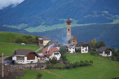 Panoramic view of idyllic mountain scenery in the Dolomites with a little village with a beautiful church tower, 2020
