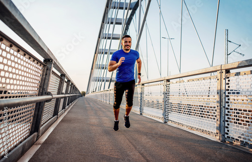 Jogging. Young man running over the bridge. Sport, fitness, recreation concept © bobex73