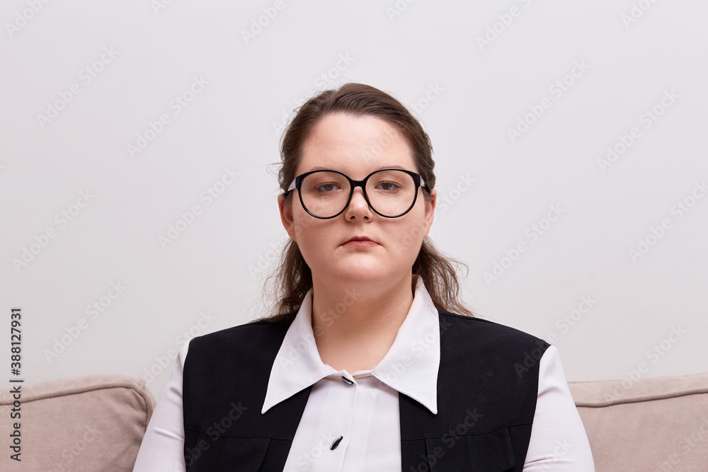Portrait of a young beautiful brunette woman with black-rimmed glasses, looking at the camera. Plus size model. Portrait of a young beautiful brunette woman with black-rimmed glasses, looking at the camera. Plus size model.