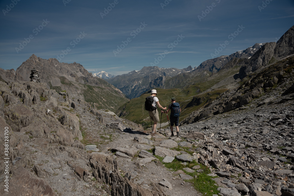 a man and a woman descend from the Col de Chaviere towards the Peclet Polset hut facing Mont Blanc