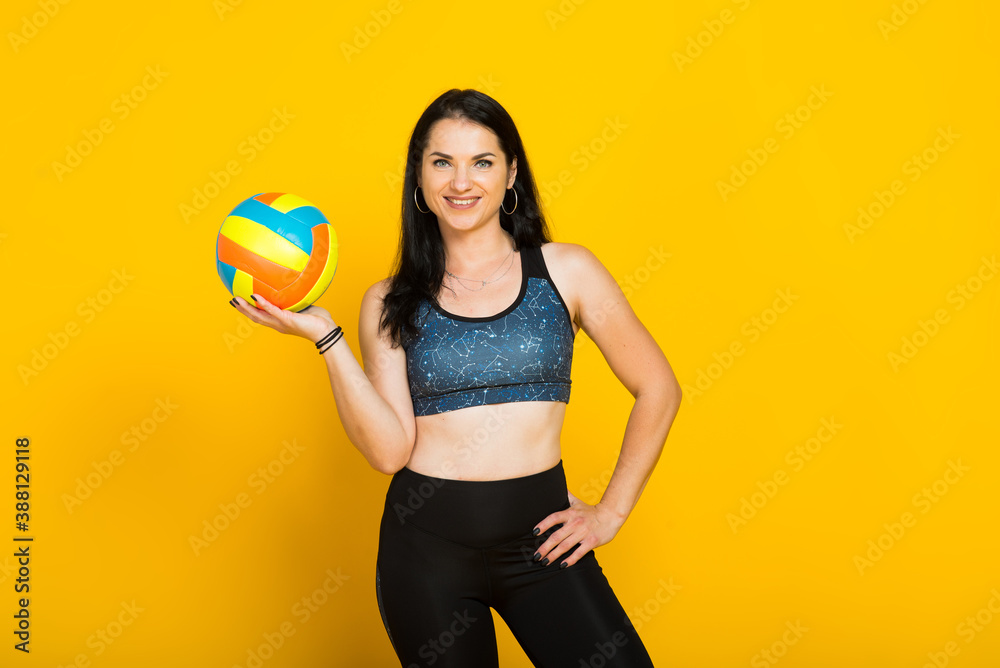 Young beautiful volleyball player isolated on yellow in studio Young beautiful volleyball player isolated on yellow in studio