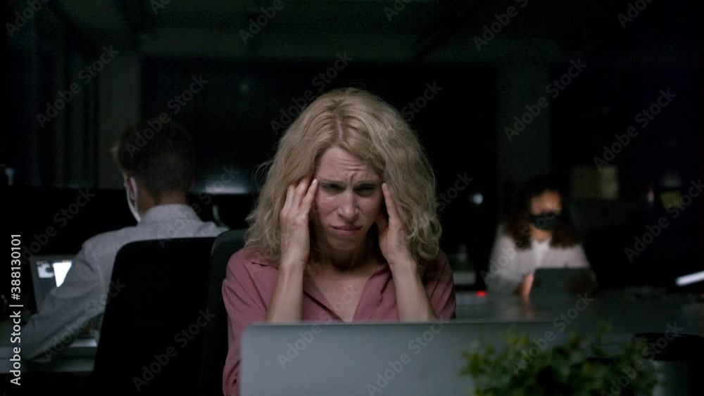 Tired business woman working late indoors in office at night. Tired business woman working late indoors in office at night.