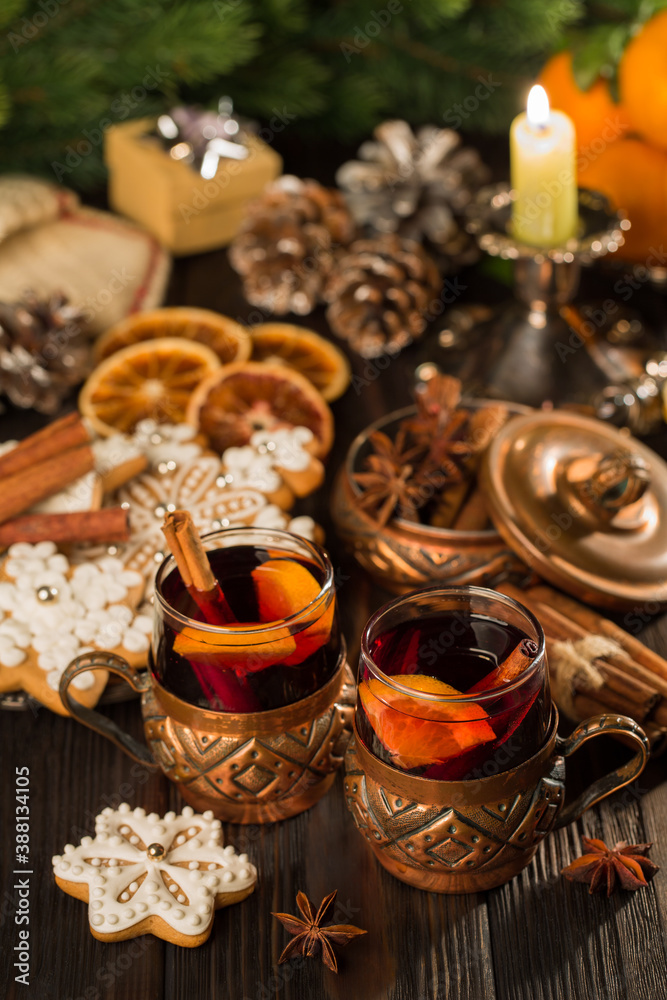 Glasses of mulled wine with cinnamon, tangerines and gingerbread on a background of candles, lights. Christmas, New Year's idea, concept Glasses of mulled wine with cinnamon, tangerines and gingerbread on a background of candles, lights. Christmas, New Year's idea, concept
