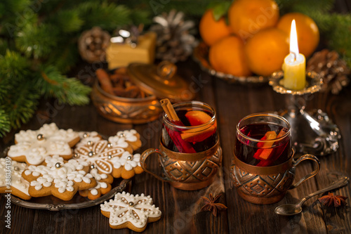 Glasses of mulled wine with cinnamon, tangerines and gingerbread on a background of candles, lights. Christmas, New Year's idea, concept