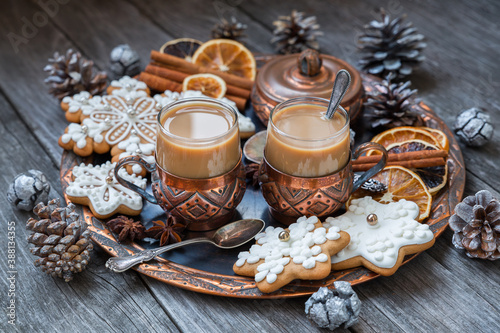 Copper cups of hot coffee with cream, cinnamon, anise and gingerbread on a copper tray. Christmas food concept in vintage style.