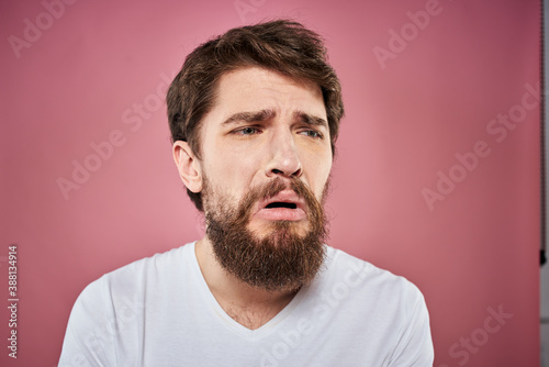 bearded man in white t-shirt emotions displeased facial expression studio pink background © SHOTPRIME STUDIO