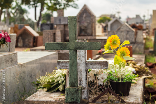 Detalhe de cruzes com flores em túmulos no cemitério.