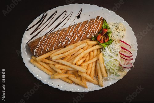 fried roll of meat with cheese with french fries and salad and onion on a plate, Serbian dish 