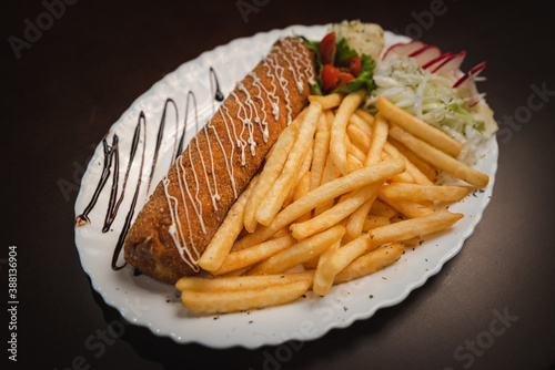 fried roll of meat with cheese with french fries and salad and onion on a plate, Serbian dish 