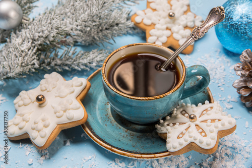 A cup of coffee with gingerbread in the shape of snowflakes on a blue snowy background. New year idea, concept © Arina B