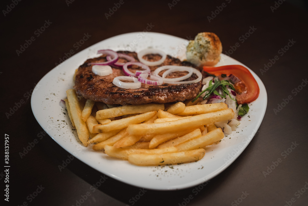 baked barbecue with french fries and salad and onion on a plate, Serbian dish baked barbecue with french fries and salad and onion on a plate, Serbian dish