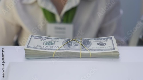 Female Hands of a Bank Employee Issues Cash in Dollars through Teller Window. Bank Clerk Gives Lend of Dollar. Employee Puts Bundles of Money on Cash Department Window. Bundle of 100 Dollar in Debt photo