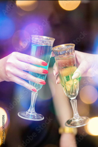 Two women's hands with glasses of champagne on a festive background.