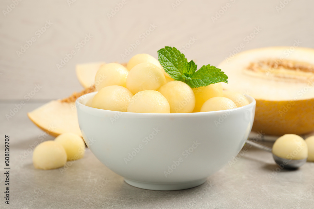 Melon balls and mint in bowl on light grey table, closeup Melon balls and mint in bowl on light grey table, closeup