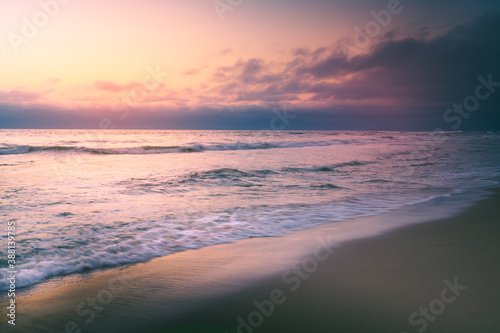 Tropical beach sunset tranquil abstract seascape with beautiful cloudy sky in yellow and pink colors on background