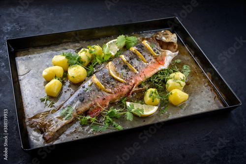 Fotografija Traditional smoked and roasted char with boiled potatoes and lemon slices offere
