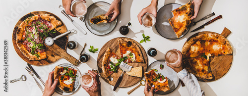 Pizza party for friends. Flat-lay of various pizzas, lager beer and peoples hands with pizza slices and glasses over white table background, top view. Fast food, comfort food, Italian cuisine concept