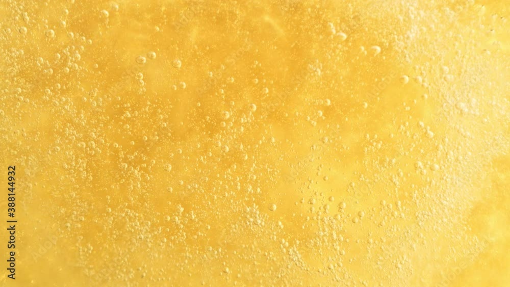 Super Slow Motion Detail Shot of Sparkling White Wine Bubbles on Golden Luxury Background at 1000fps.