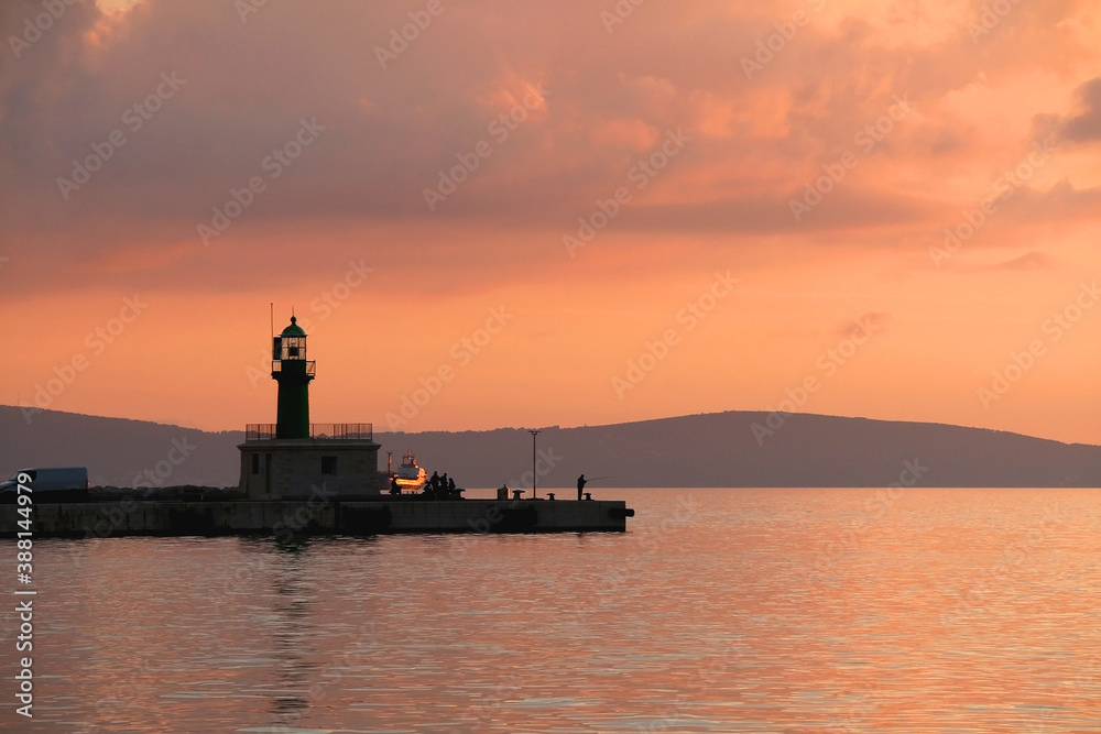 Beautiful sunset over the sea with lighthouse silhouette, in Split, Croatia.