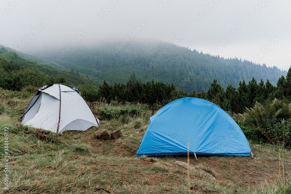 Tourist tents on the background of the carpathian mountains on a rainy and foggy day. Tourism at quarantine coronavirus covid-19 period in countryside.