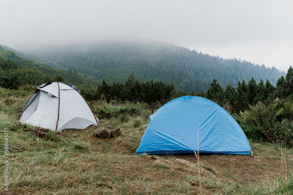 Tourist tents on the background of the carpathian mountains on a rainy and foggy day. Tourism at quarantine coronavirus covid-19 period in countryside.