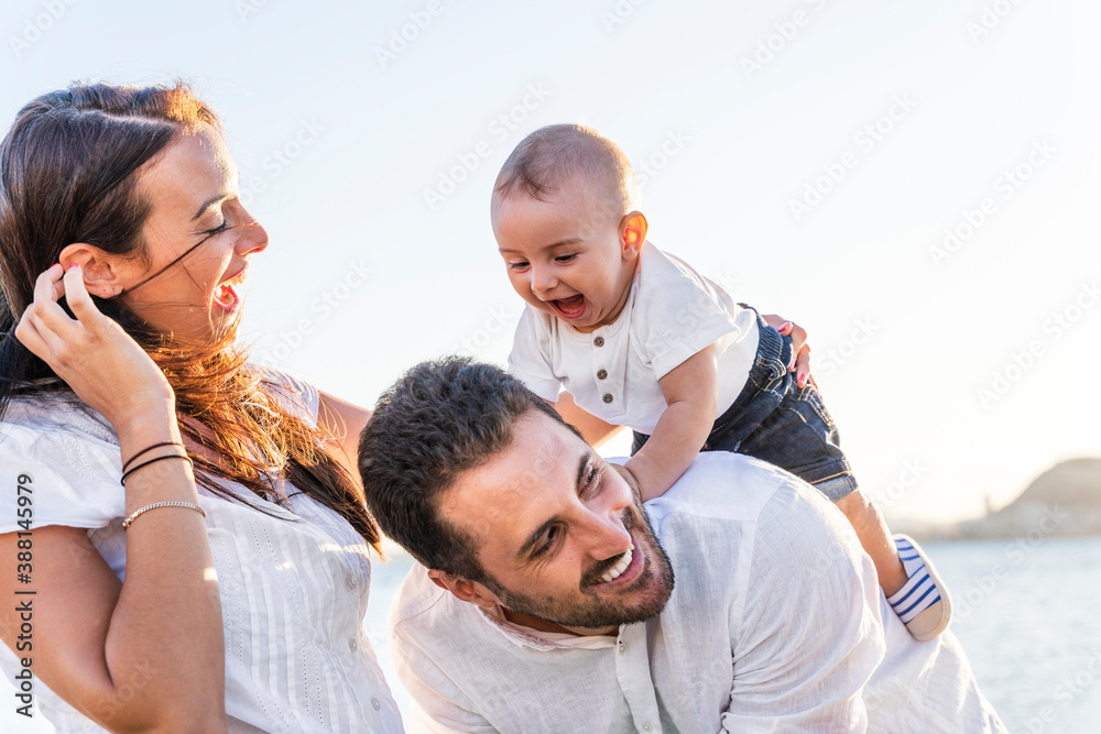 Cheerful parents playing with baby son against clear sky during sunset Cheerful parents playing with baby son against clear sky during sunset
